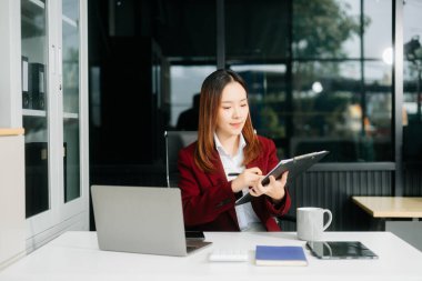 Çalışan not defteri, tablet ve dizüstü bilgisayarla çalışan Asyalı iş kadını 