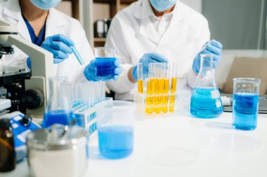 Yüksek teknolojili bir laboratuvarda iki bilim adamı biyokimyasal örnekleri analiz ediyor, mikro pipetler kullanıyor ve hassas bir şekilde gelişmiş tıbbi araştırmalar yürütüyorlar.