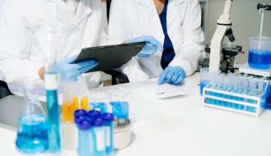 Laboratuar önlüklü bilim adamları, cam eşyalar üzerinde araştırma yapıyorlar ve modern, yüksek teknoloji laboratuvarında kimyasallarla çalışıyorlar.
