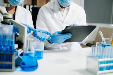 Laboratuar önlüklü bilim adamları, cam eşyalar üzerinde araştırma yapıyorlar ve modern, yüksek teknoloji laboratuvarında kimyasallarla çalışıyorlar.