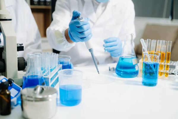 Два учёных в высокотехнологичной лаборатории анализируют биохимические образцы, используя микропипетки, и проводят передовые медицинские исследования с точностью