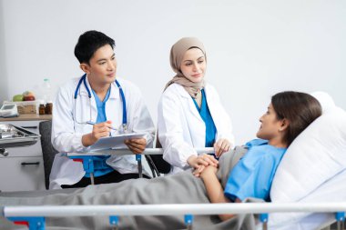 Profesyonel doktorlar bir hastayla konuşuyor, sağlık tavsiyesi veriyor, gelişmiş ekipmanlarla tedavi planı öneriyor. 