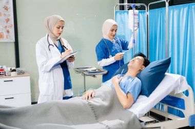 Hastane koğuşundaki bir hastayla ilgilenen doktorlar takım çalışması, profesyonellik ve sağlık hizmetleri sergiliyor.