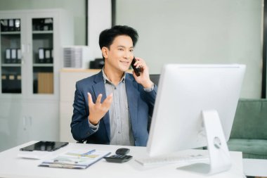 Asyalı işadamı tabletleri, laptopları ve ofiste yaptıkları işlerden memnun ve memnun.