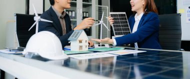 İki Asyalı mühendis, modern ofis ortamında yenilik ve sürdürülebilirliği tartışan bir güneş ve rüzgar enerjisi projesinde işbirliği yapıyorlar. Temiz enerji, takım çalışması ve ilerleme
