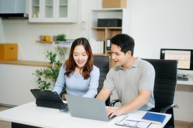 Erkek, erkek meslektaşıyla yeni projeyi tartışıyor. Genç bayan ofiste genç bir adamla konuşuyor.