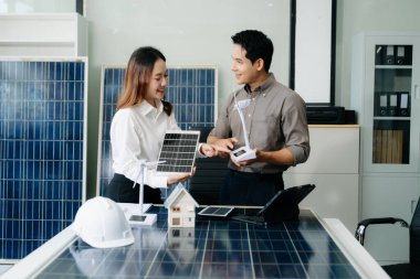 İki Asyalı mühendis, modern bir ofis ortamında yenilik ve sürdürülebilirliği tartışan bir güneş ve rüzgar enerjisi projesinde işbirliği yapıyorlar..