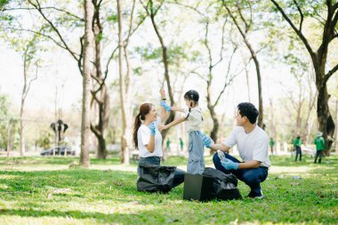 Asyalı ebeveynler ve kızları geri dönüşüm, birlik ve ekolojiyi desteklemek için ormanda çöp topluyor. Yürek ısıtan bir aşk, özen, takım çalışması ve doğa koruma sahnesi.