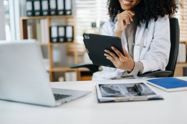 Tıbbi teknoloji konsepti. Modern hastane ofisinde dijital tablet ve laptopla çalışan bir doktor.