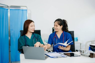 Modern bir ofiste birlikte çalışan Asyalı doktorlar ve hemşireler, klinik bir ortamda sağlık hizmetleri, danışma ve profesyonel bakımı sergilemektedirler..