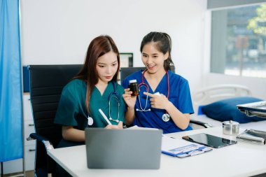 Modern bir ofiste birlikte çalışan Asyalı doktorlar ve hemşireler, klinik bir ortamda sağlık hizmetleri, danışma ve profesyonel bakımı sergilemektedirler..