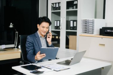 Ofis masasında dizüstü bilgisayarla finans analizi üzerinde çalışan kendine güvenen bir iş adamı. İş, muhasebe ve profesyonel iş yeri kavramları için mükemmel.