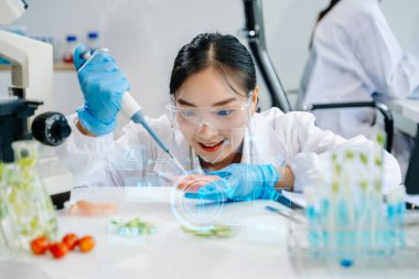 Asyalı kadın bilim adamları modern laboratuarda kimya araştırması yapıyorlar.