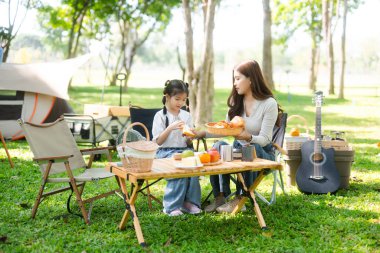 Aile yaz kampını kahve ve yiyecek kahvaltısıyla sever. Anne ve kızı piknik sırasında dışarıda kaynaşıyorlar. 