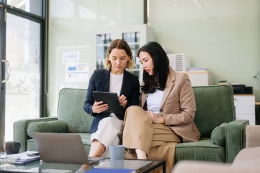 Takım çalışması ve yenilik, iki iş kadını şık bir ofis ortamında tablet kullanarak iş birliği yapıyor. Takım çalışması, liderlik ve yaratıcılık kavramları için mükemmel..