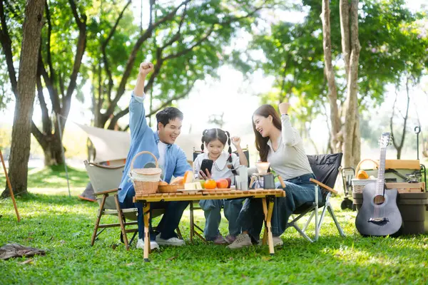 Aile yaz kampını kahve ve yiyecek kahvaltısıyla sever. Ebeveynler ve çocuklar piknik sırasında ve el kol hareketleri yaparken dışarıda kaynaşıyorlar. 