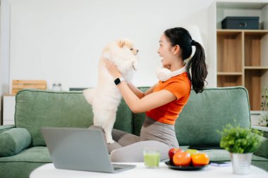 Parlak, modern oturma odasında köpeğiyle koltukta dinlenen bir kadın.