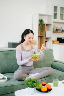 Spor yaptıktan sonra salata yiyen genç bir kadın. Aktif sağlıklı yaşam tarzı, temiz yeme konsepti