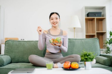  Spor yaptıktan sonra salata yiyen genç bir kadın. Aktif sağlıklı yaşam tarzı, temiz yeme konsepti