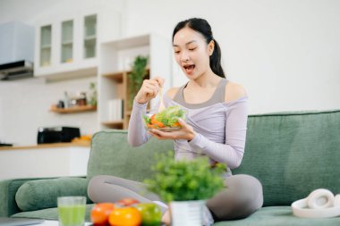  Spor yaptıktan sonra salata yiyen genç bir kadın. Aktif sağlıklı yaşam tarzı, temiz yeme konsepti