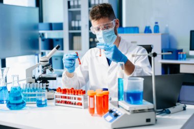 Erkek bilim adamı, biyokimyasal örnekleri analiz eden mikro pipetlerle çalışıyor.