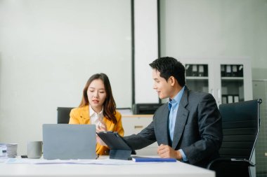 Nazik yönetici yönetici, Asyalı erkek pazarlama yöneticisiyle birlikte modern ofiste iş çözümlerini paylaşır ve tartışır.