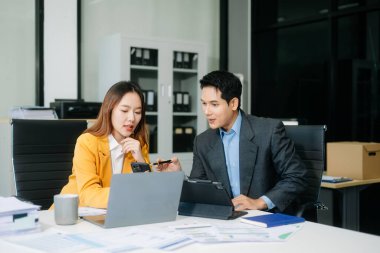 Nazik yönetici yönetici, Asyalı erkek pazarlama yöneticisiyle birlikte modern ofiste iş çözümlerini paylaşır ve tartışır.