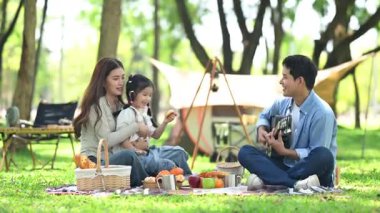 Aile yaz kampını kahve ve yiyecek kahvaltısıyla sever. Ebeveynler ve çocuklar piknik sırasında dışarı çıkıp gitar çalıyorlar.