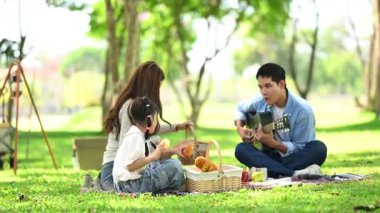 Aile yaz kampını kahve ve yiyecek kahvaltısıyla sever. Ebeveynler ve çocuklar piknik sırasında dışarı çıkıp gitar çalıyorlar.