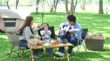 Aile yaz kampını kahve ve yiyecek kahvaltısıyla sever. Ebeveynler ve çocuklar piknik sırasında dışarı çıkıp gitar çalıyorlar.