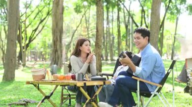 Aile yaz kampını kahve ve yiyecek kahvaltısıyla sever. Ebeveynler ve çocuklar piknik sırasında dışarı çıkıp gitar çalıyorlar.