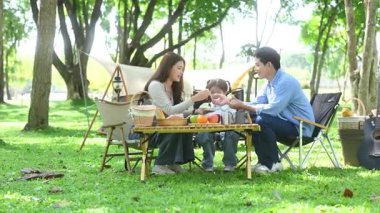 Aile yaz kampını kahve ve yiyecek kahvaltısıyla sever. Ebeveynler ve çocuklar piknik sırasında dışarıda kaynaşıyorlar. 