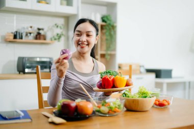 Genç bayan taze meyve, sebze ve besleyici malzemelerle sağlıklı tarifler hazırlıyor..