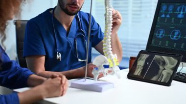 Muayene sırasında hastaya insan omurgası modelini açıklayan doktor