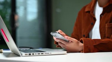 İşadamlarının elleri smatphone kullanıyor ve ofiste dizüstü bilgisayarla çalışıyor.