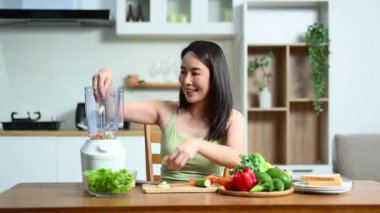 Kadın mutfakta blender kullanarak sağlıklı yemek hazırlıyor.