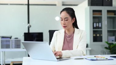 Modern ofis ortamında dizüstü bilgisayarda çalışan iş kadını