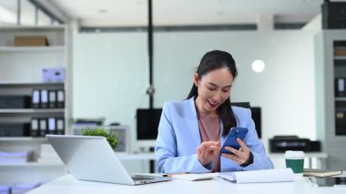 modern ofiste akıllı telefon kullanırken gülümseyen kadın