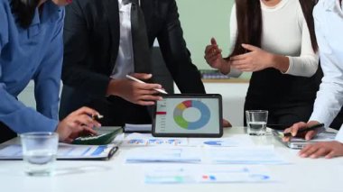 İş ortakları, günışığıyla aydınlanan modern ofis ortamında bir girişimin birden fazla dijital cihazdaki finansal büyümesini inceliyor.