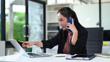 İş kadını telefonda konuşurken dizüstü bilgisayar ekranına işaret ediyor