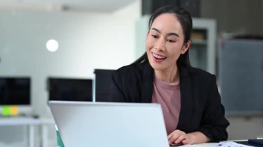 Modern ofis ortamında dizüstü bilgisayar kullanırken gülümseyen iş kadını