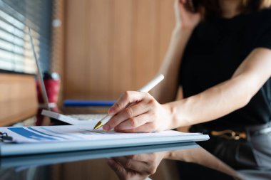 Gündüz vakti modern ofiste beyaz kalemle belge üzerine yazı yazan kadını kapat