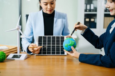 İki kadın ekolojik dünya modellerini, güneş panellerini ve yenilenebilir enerji çözümlerini planlamak için akıllı bir evi analiz ediyor. 