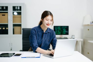 Ofiste dizüstü bilgisayarda çalışan gülümseyen bir iş kadını. Zarif ve odaklanmış, uzak çalışma, dijital iş, serbest çalışma ve teknoloji girişimleri temaları için mükemmel..