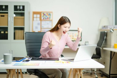 Kadın, modern bir yaratıcı ofiste tablet üzerinde çalışırken başarıyı kutluyor. Başarı, keyif ve dijital serbest yaşam tarzını yakalıyor..