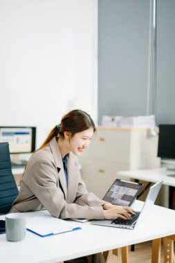 Modern bir ofiste dizüstü bilgisayar ve tablet üzerinde çalışan kendine güvenen bir iş kadını. Zarif ve odaklanmış, uzak çalışma, dijital iş, serbest çalışma ve teknoloji girişimleri temaları için mükemmel..