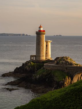 Finistere, Brittany, Fransa sahilindeki Petit Minou Deniz Feneri 'nin dikey görüntüsü dramatik kayalar ve sakin okyanuslarla aydınlatılıyor..