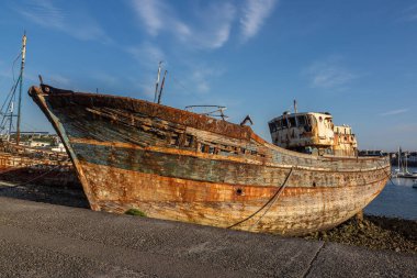 Bereketli mavi gökyüzünün altında, Camaret-sur-Mer, Brittany 'deki liman silonunda yıpranmış ve paslı bir balıkçı teknesi..