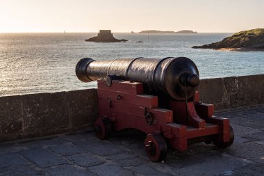 Tarihi Saint-Malo, Brittany, Fransa kıyı kalesinin taş surlarında eski demir top. Gün batımında Manş Denizi manzarası.