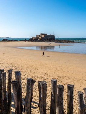 Gün batımında Saint Malo 'daki Mole des Noires iskelesinde kırmızı ve beyaz deniz feneri. Fransa 'nın Brittany sahilinde akşam ışığı. Arkasında deniz ve kasaba var..